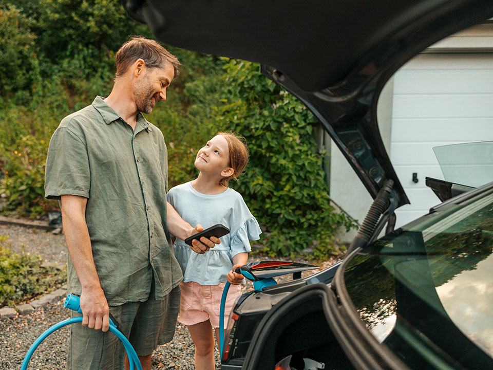 Man och dotter laddar elbil.