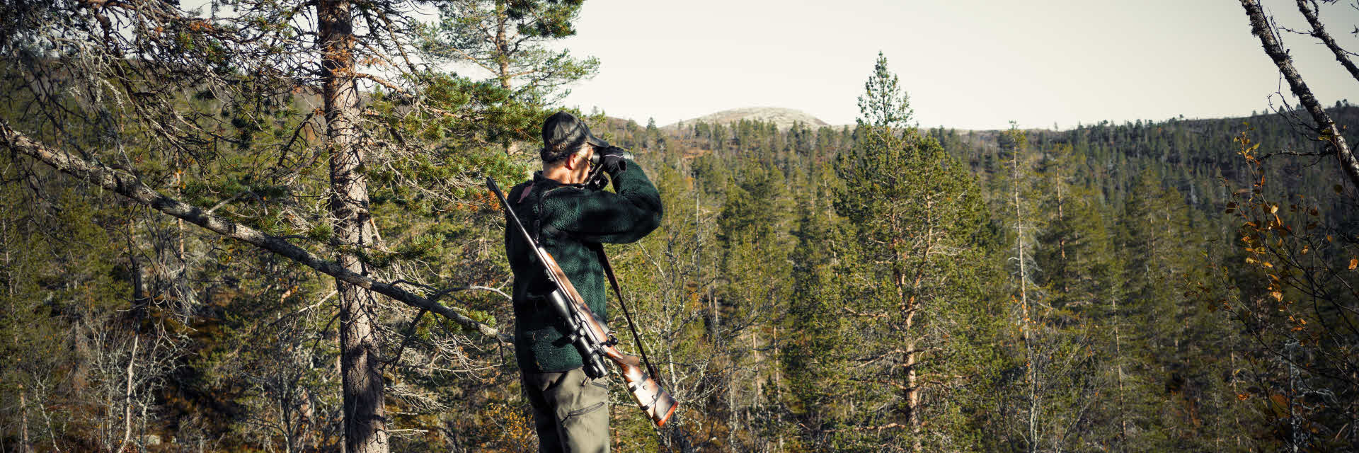 Fotograf: Stefan Isaksson
Bildbyrå: Johnér Jägare med kikare som spejar ut över en skogsbrant.