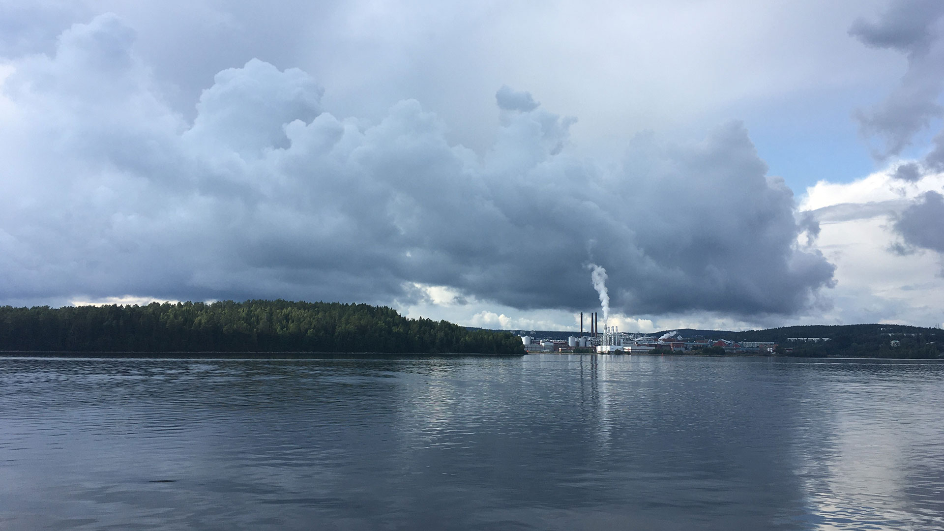 Fotograf: Tove Bratthäll Industri som släpper ut rök. I förgrunden en stor vattenyta.