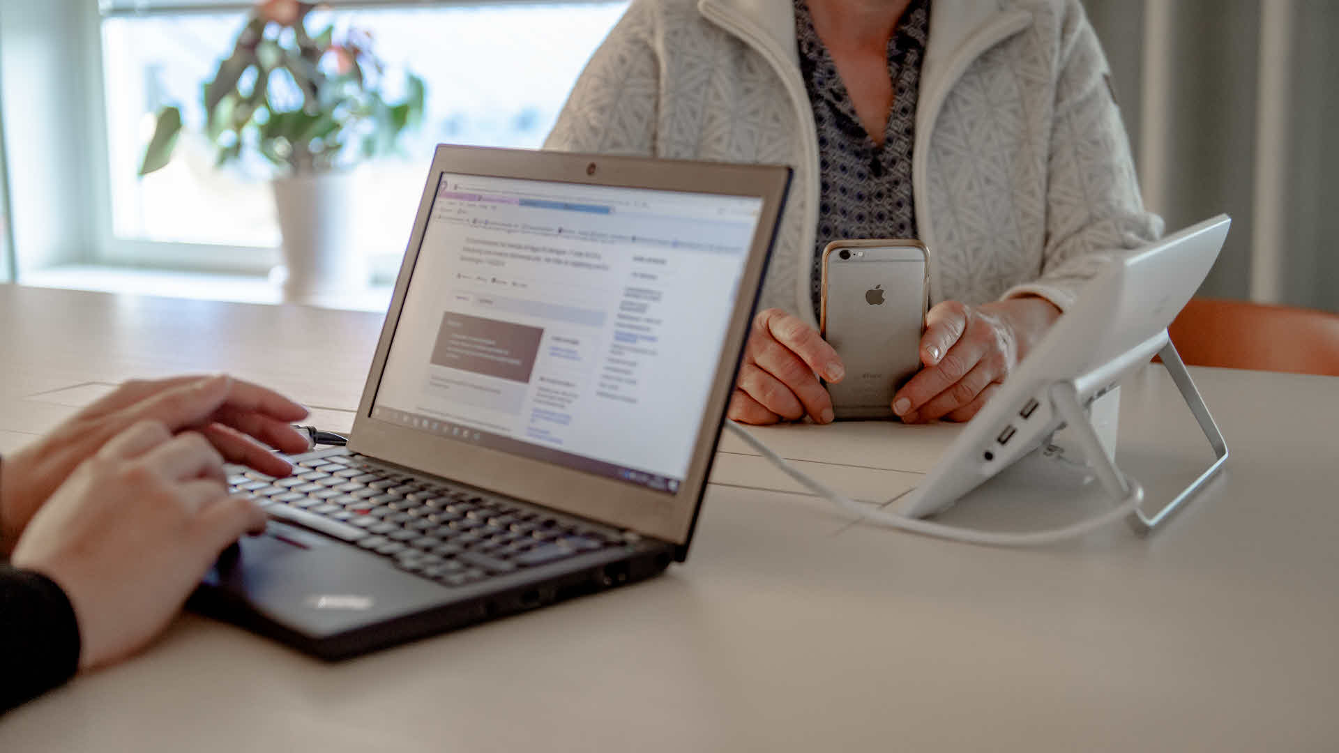 Fotograf: Naturvårdsverket Ett par händer på ett tangentbord, en person håller i en mobiltelefon.