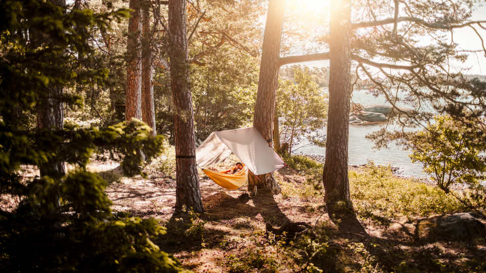 Man kopplar av i hängmatta vid sjöstrand