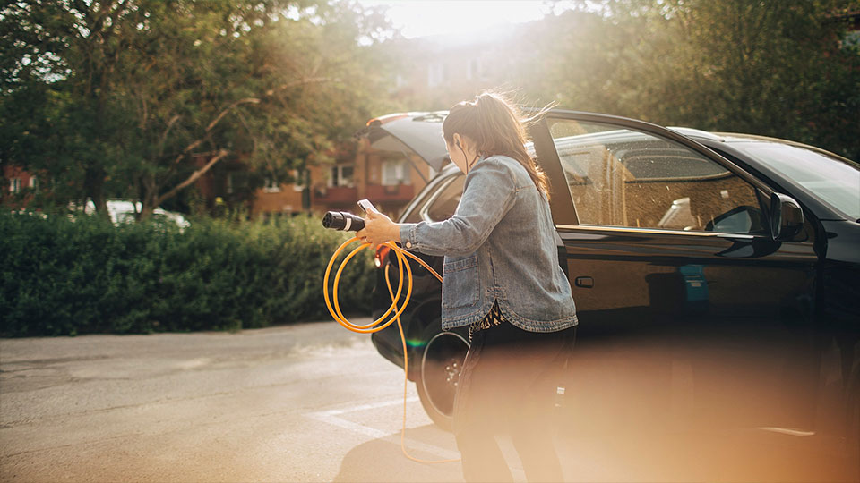 Fotograf: Maskot
Bildbyrå: Johnér Kvinna som ska ladda sin elbil vid garageuppfart