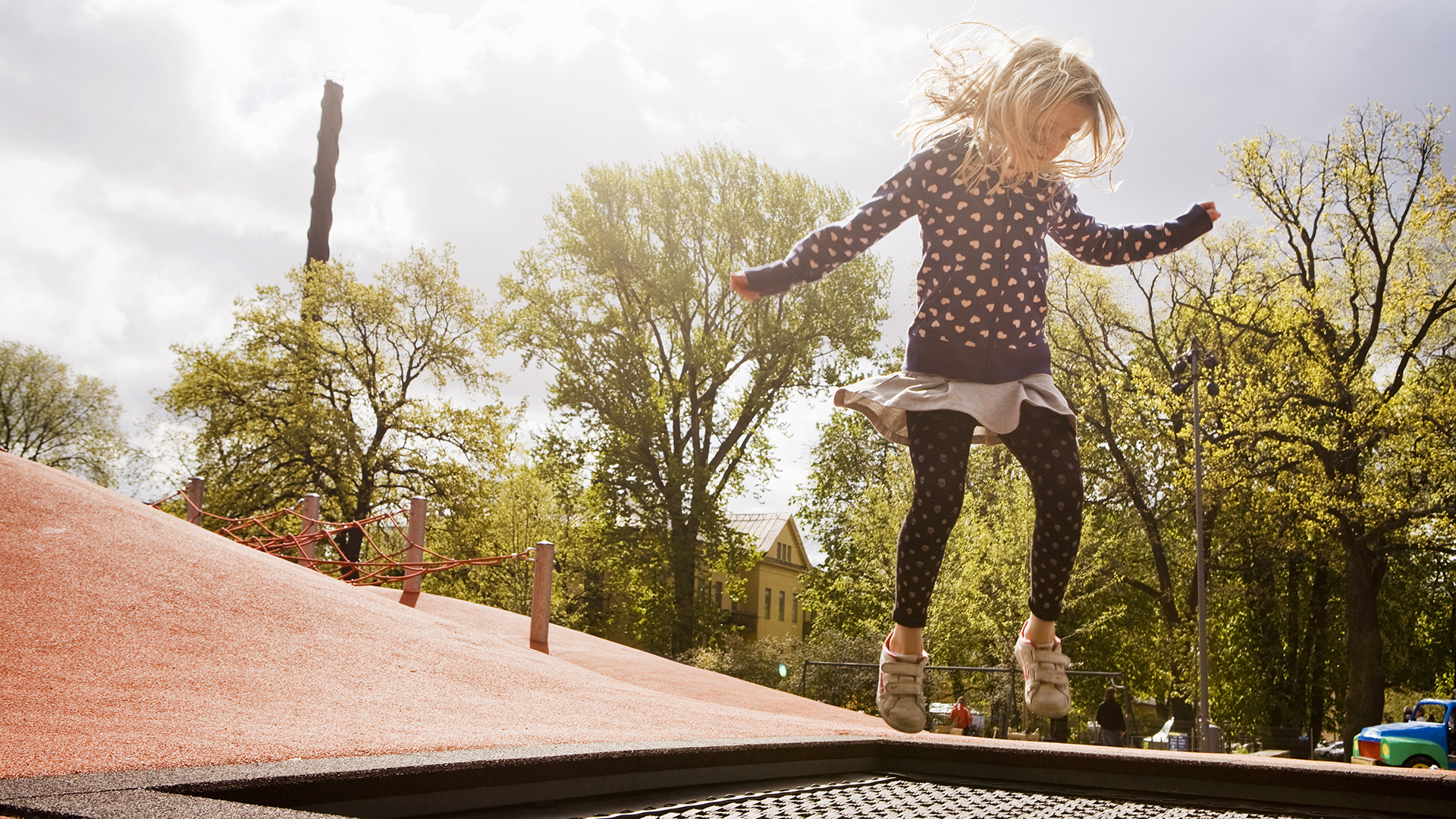Fotograf: Susanne Kronholm. Flicka hoppar på en lekplats.